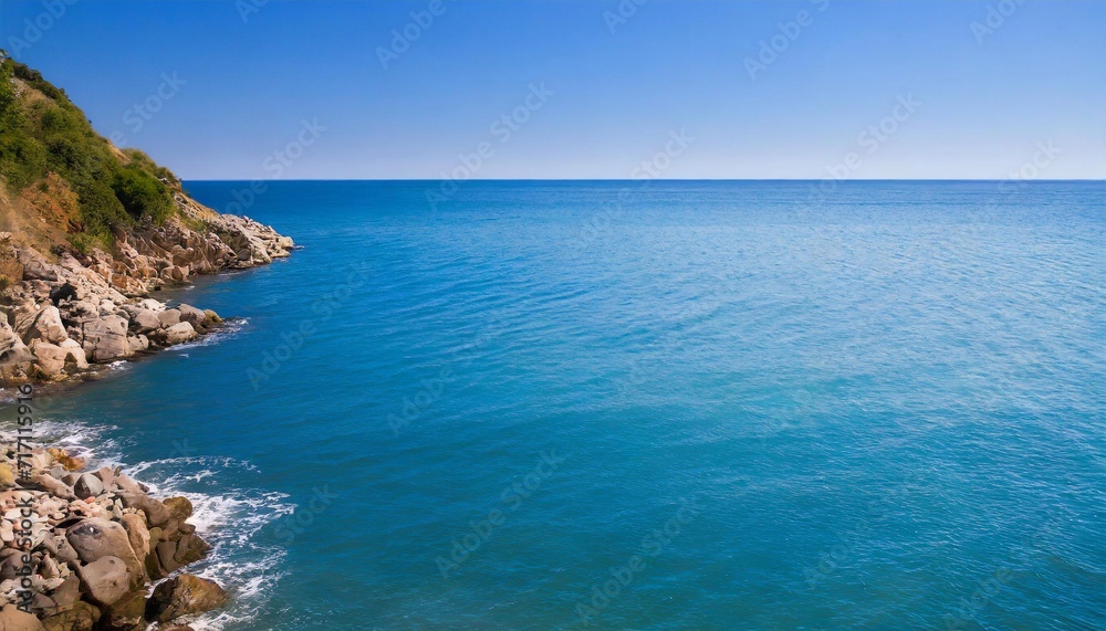 Clear sky and blue sea with stone shore.