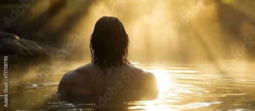 Back view of Jesus Christ bathed in morning sunlit water.
