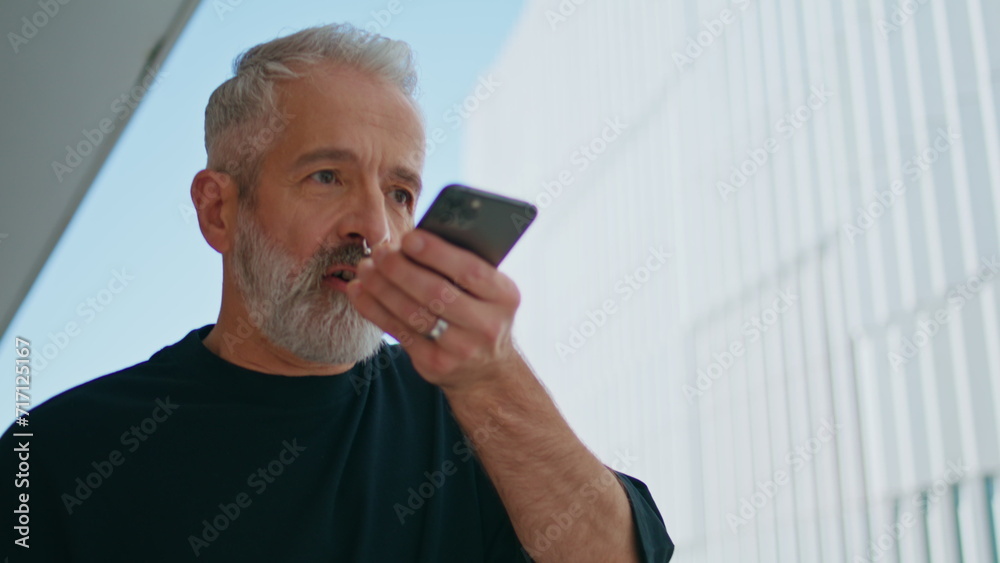 Elderly man recording message on smartphone closeup. Good looking senior using Elderly man recording message on smartphone closeup. Good looking senior using
