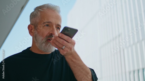Photography Elderly man recording message on smartphone closeup
