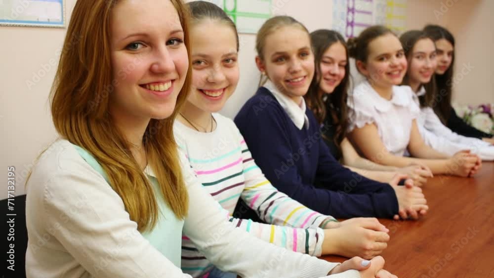 Seven young girls sitting at the table and looking at the camera Seven young girls sitting at the table and looking at the camera