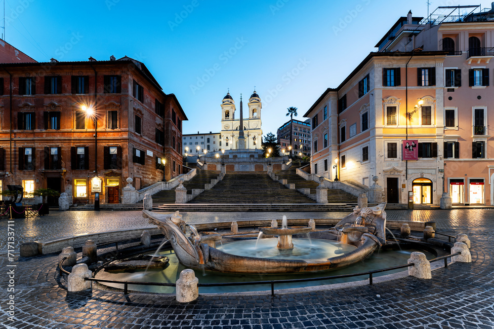 The famous Spanish steps with fountain and illuminated streetlights during blue hour in Rome, Italy