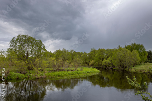 Dramatic sky against the background of a spring landscape by the river