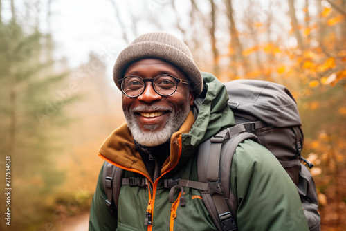 Smiling hiker with backpack in an autumn forest, enjoying the outdoor adventure.