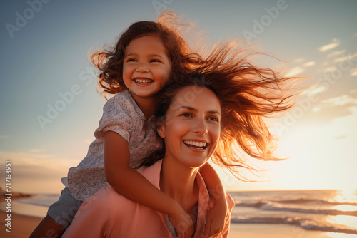 Mother and daughter enjoy a joyful moment on the beach, with genuine smiles and the sea in the background.