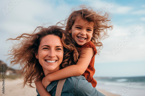 Mother and daughter enjoy a joyful moment on the beach, with genuine smiles and the sea in the background.