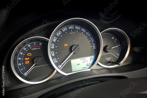 Detail of dashboard of modern car with odometer and instruments showing values as rpm and fuel level.