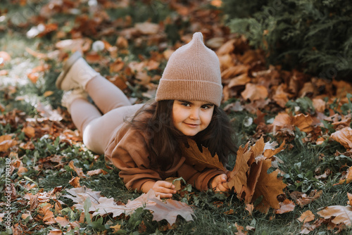 Cute little brunette girl lying on the grass in autumn