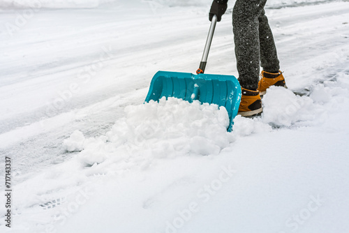 Cleaning snow from street in winter with shovel after snowstorm. Cleaning sidewalk from snow on a winter day.