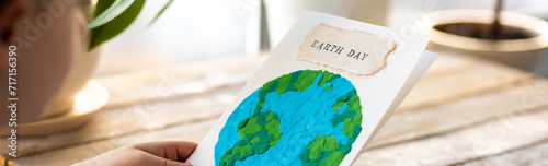 Banner. Concept of raising awareness about the environmental issues on the Earth day. Kid doing craft postcard with planet on it. Promoting sustainable lifestyle, environment protection photo