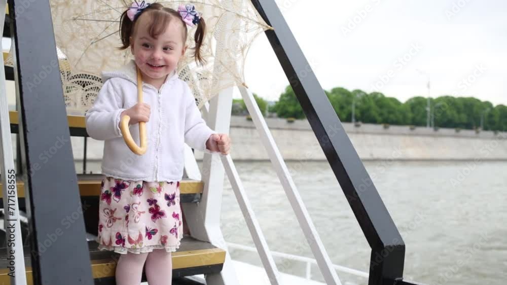 Little girl stands on the stairs of the ship and shows thumbs up Little girl stands on the stairs of the ship and shows thumbs up