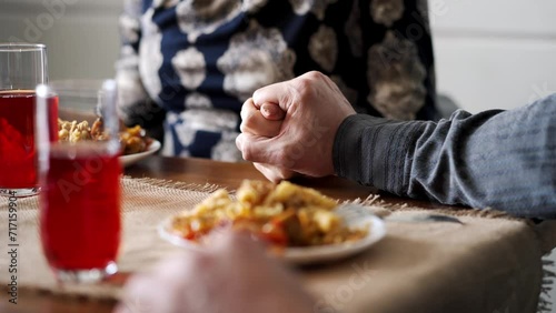 Happy family holding hands and praying with closed eyes before having a meal. Caucasian christians parents with small daughter arms together thanksgiving to god on dining table photo