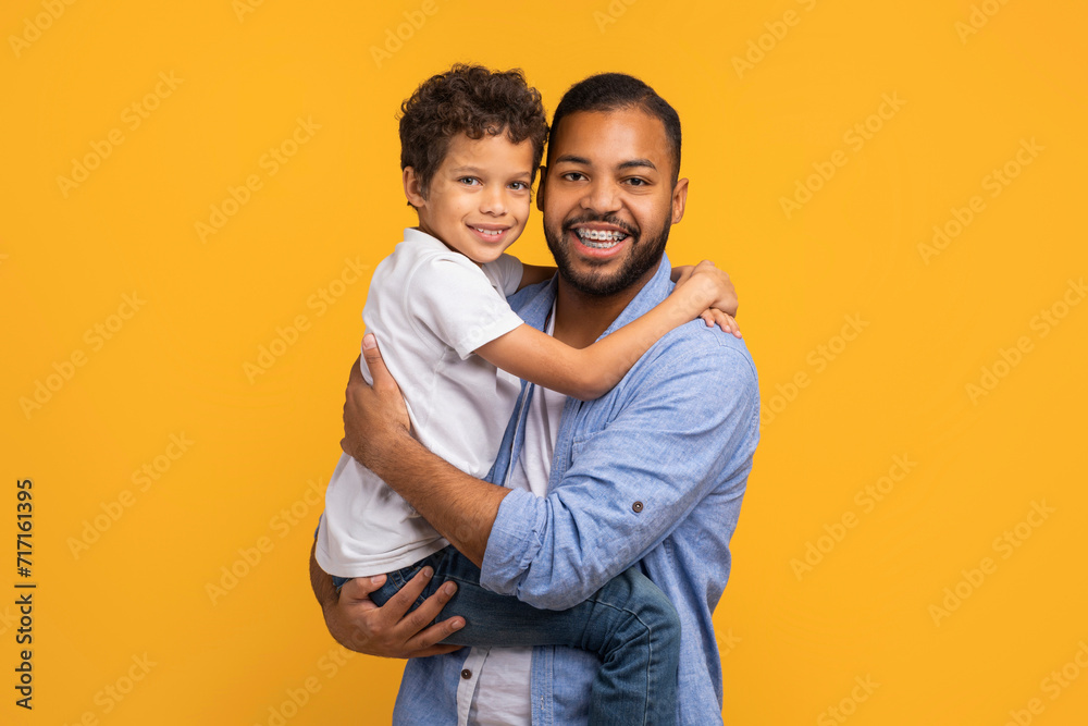 Happy black father lifting his little son and hugging Happy black father lifting his little son and hugging