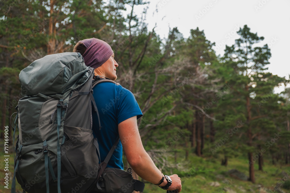 Hiking tourism adventure. Backpacker hiker man looking at beautiful view. Hiker tourist with backpack walking in green forest. Back view man enjoy hike trekking tourism active vacation