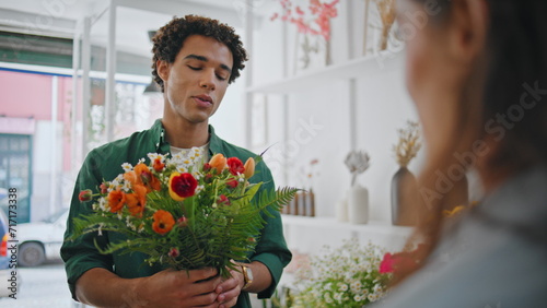 Joyful customer present flower to seller lady in plant store. Romantic concept.