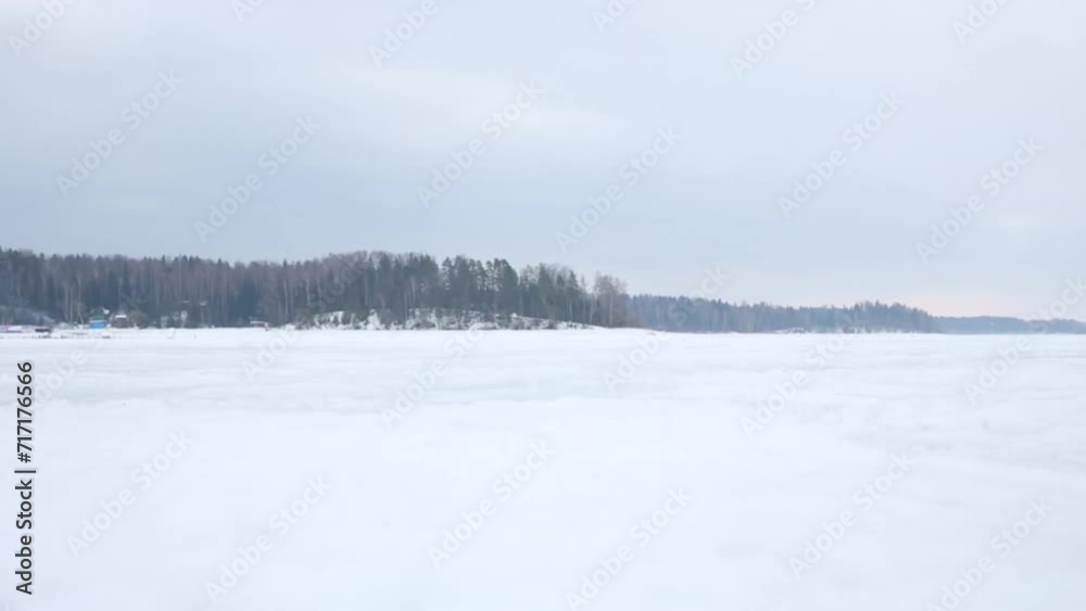 Father and son in helmets ride on skidoo on frozen river