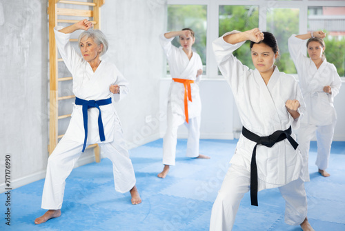 Female students of martial arts academy look at Kata karate teacher conducts classes and performs movements and fighting techniques together