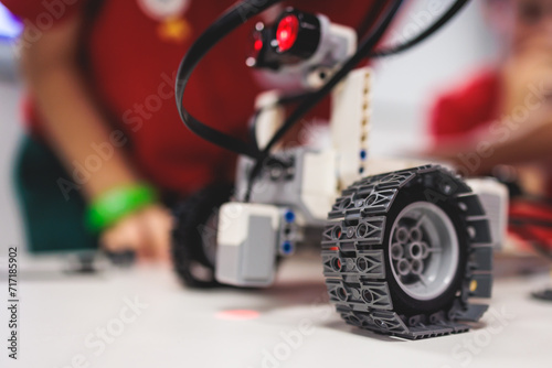 Group of diverse children kids with robotic vehicle model, close-up view on hands, science and engineering lesson in a classroom, making, coding and programming a robot in a school, robotics projects
