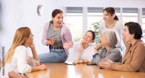 during morning five minutes, colleagues sit at table and animatedly discuss set of tasks for day. Young contemporary female team leader sitting on table and leads staff meeting.Group work, teamwork