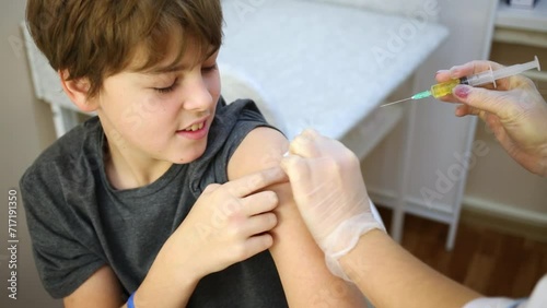 Female doctor prepares arm of boy to make injection. photo