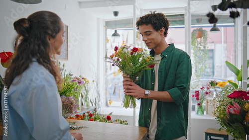 Emotional shopper give flower present gift to beautiful florist woman in store. photo