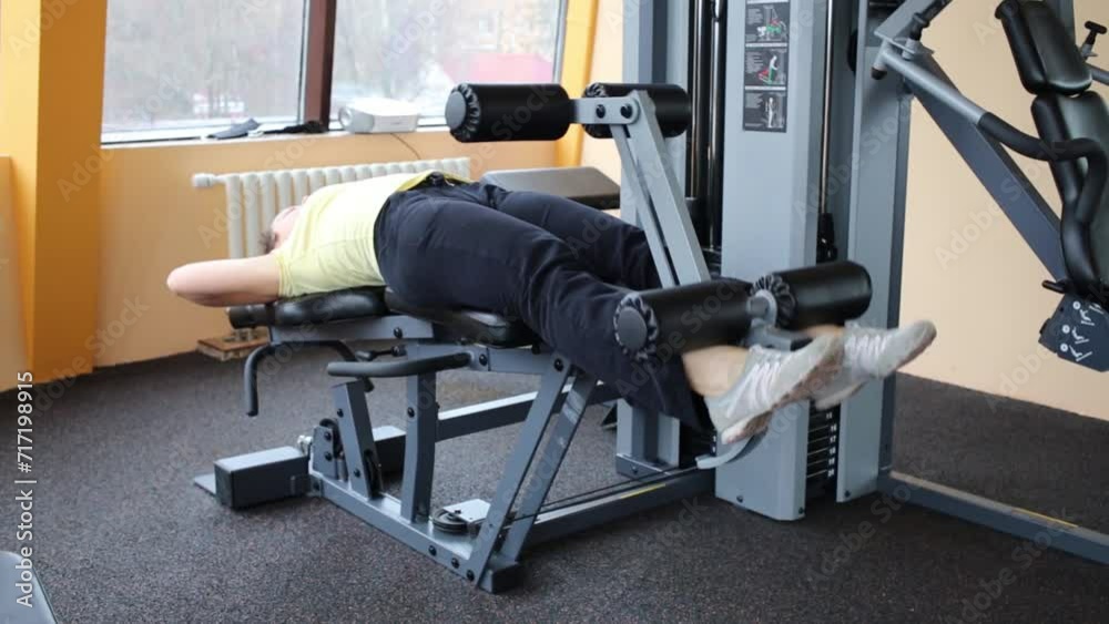 woman does exercise for leg muscles on simulator in fitness club woman does exercise for leg muscles on simulator in fitness club