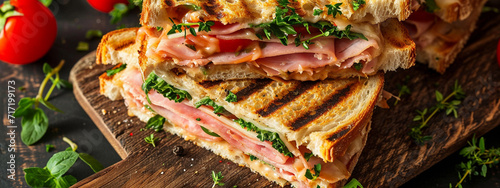 Grilled and pressed toast with smoked ham, cheese, tomato and lettuce served on wooden cutting board