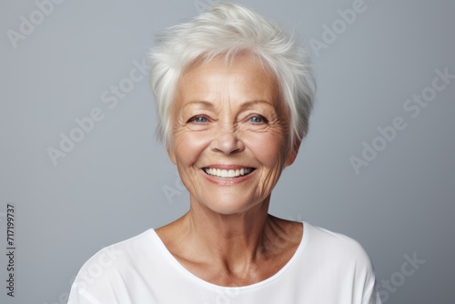 Portrait of a happy senior woman looking at camera against grey background