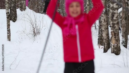 Girl slides on skis from hill next to two adults and two children on winter day