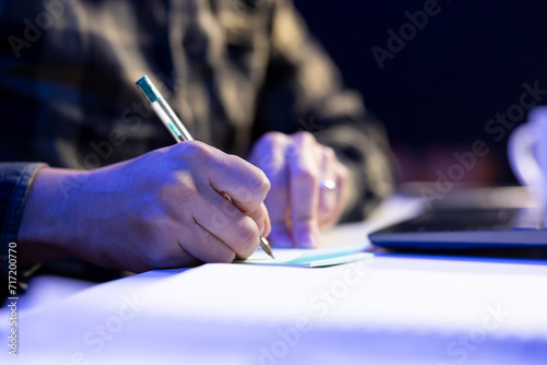 Selective focus on person writing on notepad at table, studying and researching of information. Closeup of an individual using pen to take down notes on paper, planning the day and completing tasks.