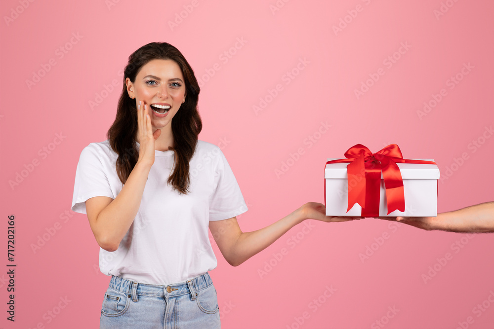 Hand of young caucasian man give box with red ribbon to happy shocked woman