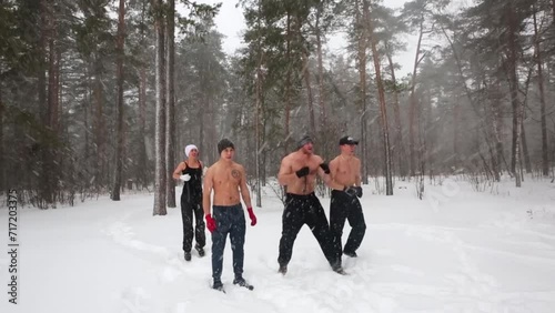 Three bare-chested guys and girl jump warming up at sportsground photo