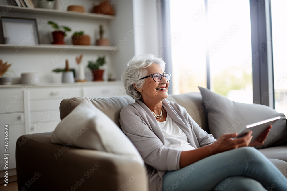 Elderly lady with glasses smiling using a tablet at home browsing internet or watching videos Elderly lady with glasses smiling using a tablet at home browsing internet or watching videos