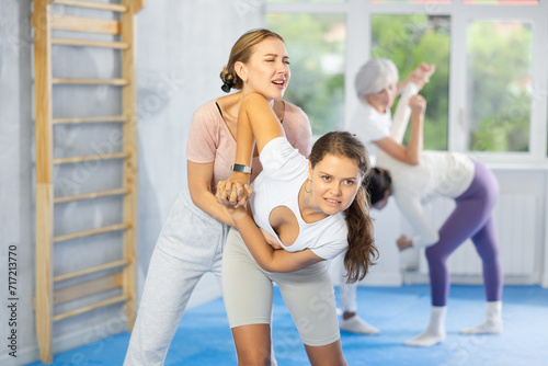 Woman and girl in gym perform basic elements of krav maga self-defense system. Preparation of athletes before competitions