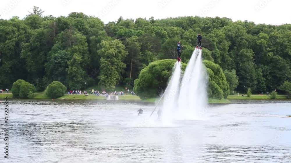 Athletes flyboard and accompanying them on jet skis on lake in park. Athletes flyboard and accompanying them on jet skis on lake in park.