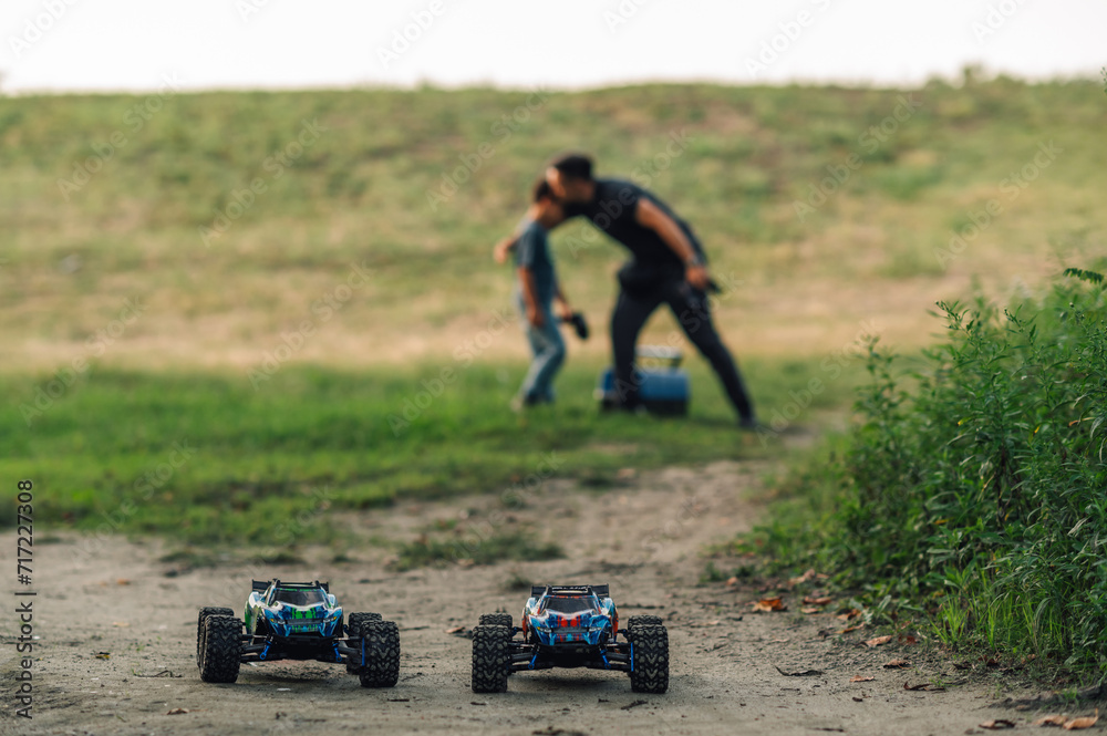 Two toy cars in nature with father and son in the background. Two toy cars in nature with father and son in the background.