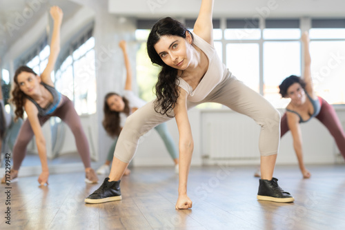 Active females exercising dance moves in a modern dance studio