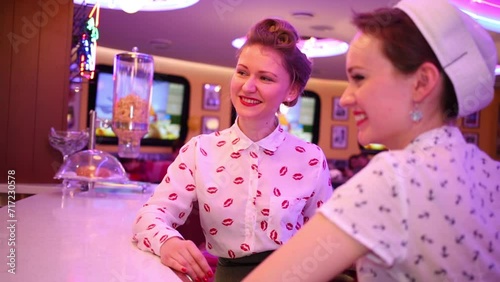 Two happy women smile near bar counter in restaurant. photo