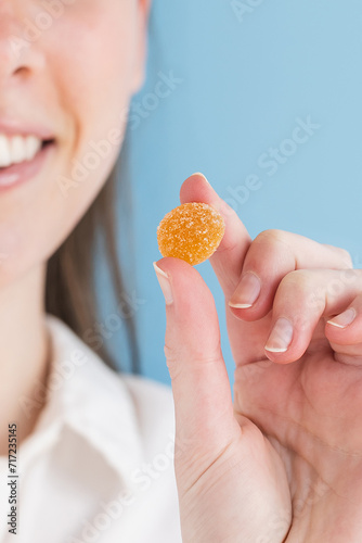 Woman holding orange gummy vitamin in hand