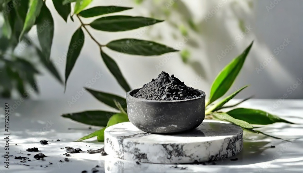 Presented on a white podium adorned with green leaves, the activated bamboo charcoal extract provides numerous advantages for the skin. - obrazy, fototapety, plakaty 