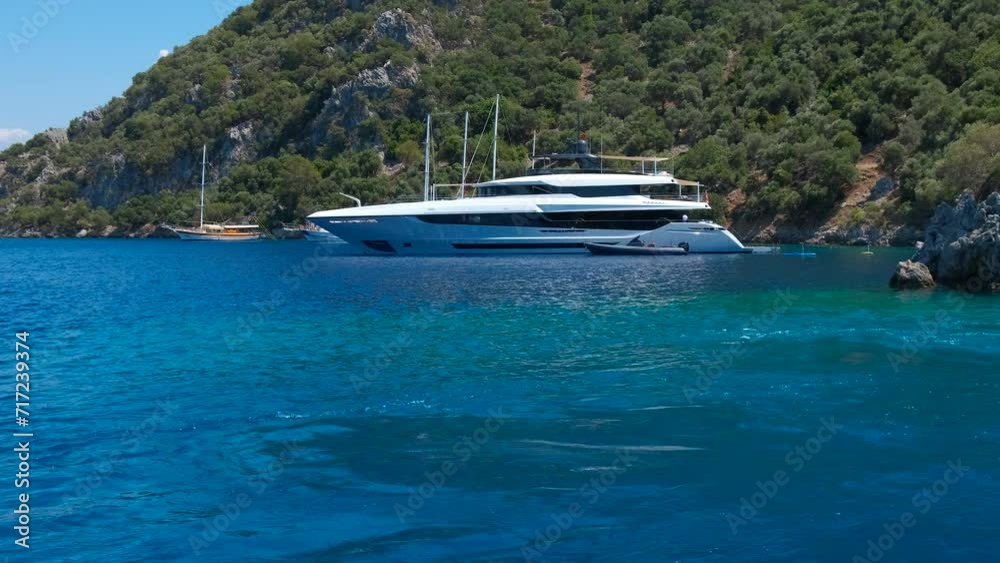 Docked excursion yacht by beach. A big luxury yacht stop moored by the exotic coasts in blue sea in summer. A concept of summer cruise and sea trip. Docked excursion yacht by beach. A big luxury yacht stop moored by the exotic coasts in blue sea in summer. A concept of summer cruise and sea trip.