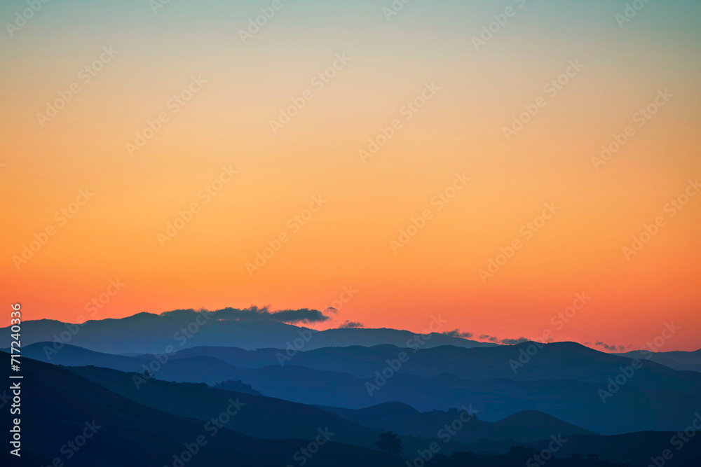sunset, sunrise in the silhouetted mountains, hills, 