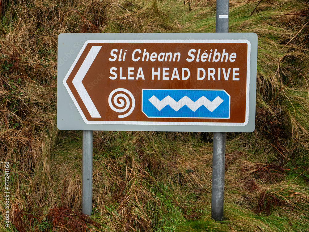 Directional sign Slea Head Drive in English and Irish Language, popular travel area with amazing nature scenery and viewpoint. County Kerry, Ireland.