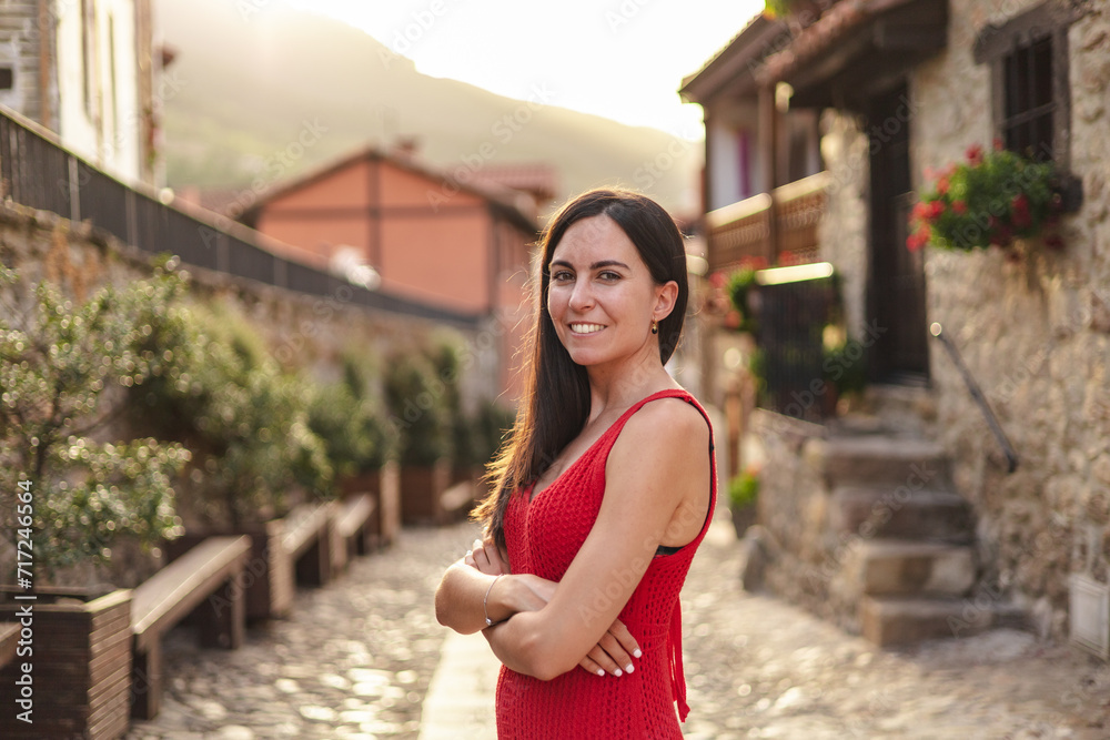 Portrait of young hispanic woman standing with crossed arms. She is in a rural town during sunset.