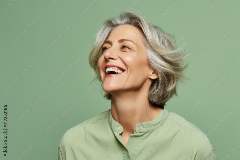 Mature woman with grey hair smiling and looking up on green background Mature woman with grey hair smiling and looking up on green background