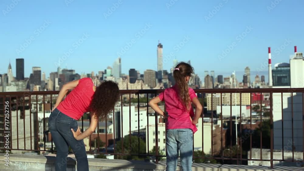 Young woman and girl do side bends on roof against blue sky. Young woman and girl do side bends on roof against blue sky.
