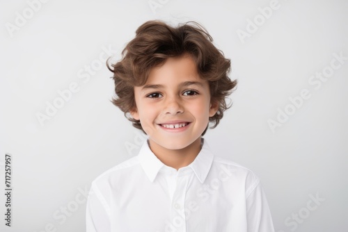 Portrait of a cute little boy in a white shirt on a gray background