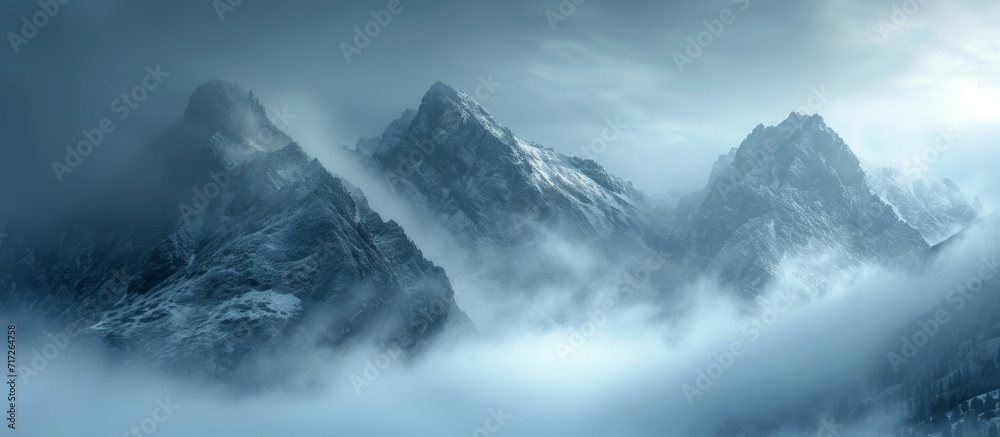 Foggy high mountain landscape with cloudy peaks at dawn in early spring.