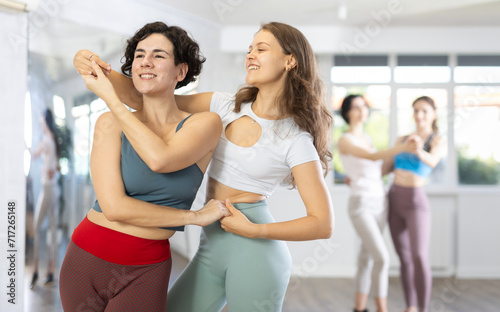 Two cheerful young female dancers having fun in dance studio, dancing intimate and rhythmic bachata moves as pair.. © JackF