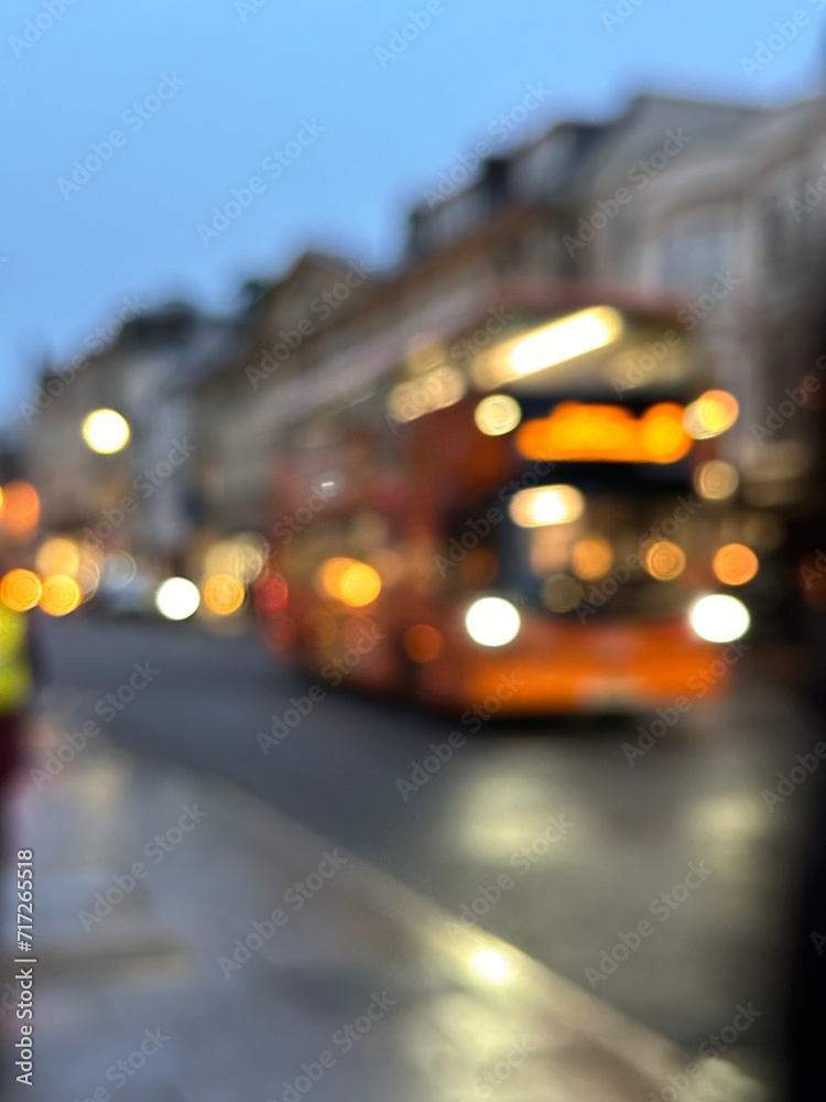 Blurred shot of a bus passing through city street, evening city lights glowing cozy